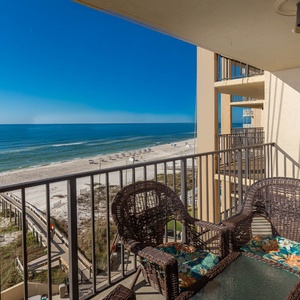 Enjoy the serene beach view from the balcony, featuring cozy wicker chairs and a glass table for relaxation