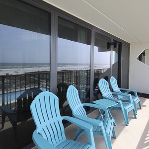 Enjoy stunning beachfront views from the balcony, featuring bright blue chairs for relaxation and leisure