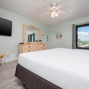 This bedroom features a comfortable bed, a TV for entertainment, and a serene view through the window