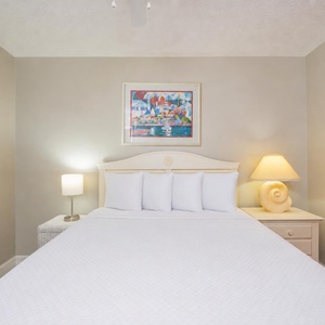 Delight in peaceful rest beneath warm lamp glow and colorful coastal art in the guest suite with a queen bed