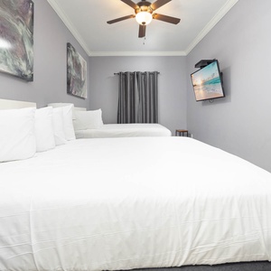 Inviting guest room with two queen beds, a TV for entertainment, and calming wall art for a restful vibe