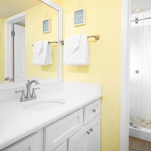 Sleek white vanity and a walk-in glass shower in the master bathroom, creating a cheerful and refreshing space