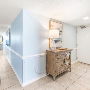 Bright entryway featuring light blue walls, a decorative console table, and a welcoming lamp, leading to the living area