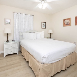 Guest bedroom featuring a queen bed, nightstands, and coastal artwork for a relaxing retreat