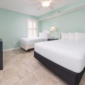This guest room features two comfortable beds, a full and a twin, a flat-screen TV, and soothing mint-green walls