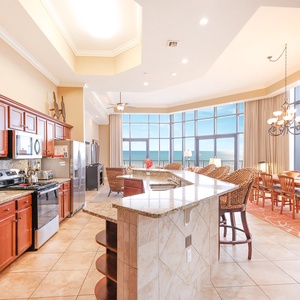 This kitchen features rich wood cabinetry, stainless appliances, and a stunning beachfront view through large windows