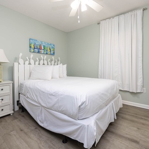 Serene guest room featuring a queen bed, soft linens, and cheerful decor for a restful getaway