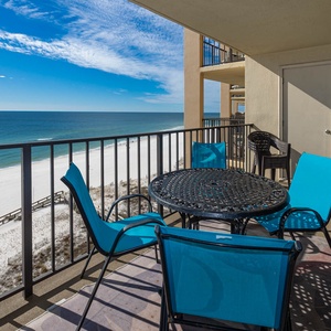 Relax on the balcony with turquoise chairs and a round table, enjoying breathtaking views of the beach