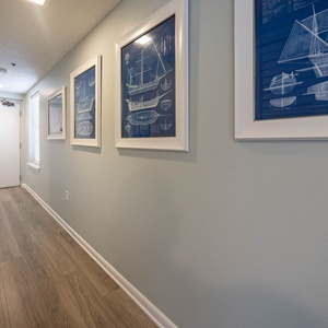 Bright hallway featuring nautical-themed artwork, leading to the entrance with natural light filtering through the window