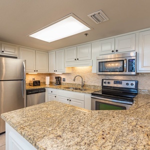 Modern kitchen features granite countertops, white cabinetry, and a breakfast bar area, enhancing your culinary experience
