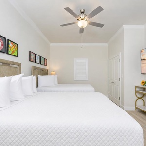 Inviting guest bedroom featuring two queen beds, vibrant artwork, and a large TV