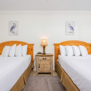 The bedroom features two cozy beds, a charming nightstand, and lovely bird artwork, perfect for a restful stay