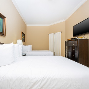 This cozy guest bedroom features two queen beds, a flat-screen TV, and charming turtle artwork on the walls