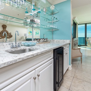 Prepare drinks at the sleek wet bar area, with stylish glassware, wine cooler, and a view that invites socializing