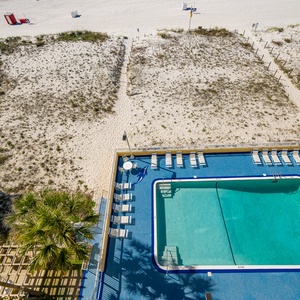 A refreshing pool area features lounge chairs and a view of the sandy beach, perfect for relaxation and fun in the sun