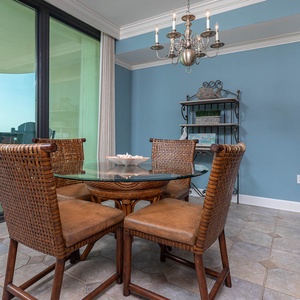 Dine comfortably at the glass-top table surrounded by woven chairs, with a view of the outdoor seating area