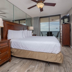 Elegantly decorated master bedroom features a king bed, elegant wooden furniture, and a balcony view of the beach