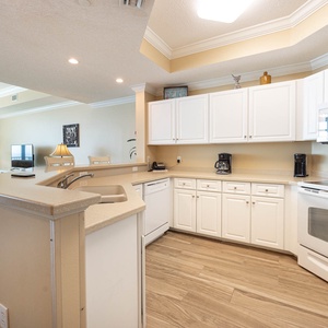 Prepare meals in this kitchen with sleek cabinetry, white appliances, and spacious countertops