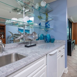 Delight in the stylish wet bar with a drink, decorative accents, sleek countertops, ice maker, and a view of the beach