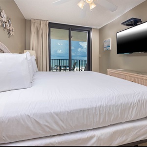 Comfortable master bedroom with a large king bed, stylish decor, and a view of the balcony