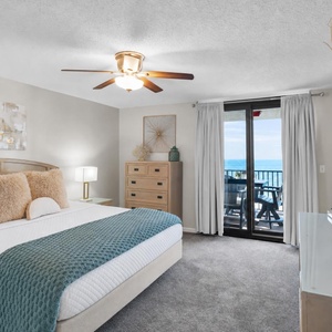 The cozy master bedroom features a plush king bed, modern decor, and a balcony with a view of the tranquil gulf waters