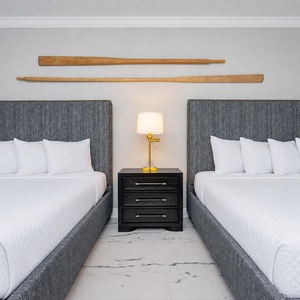 Inviting guest room featuring two queen beds, a stylish bedside lamp, and decorative wooden accents