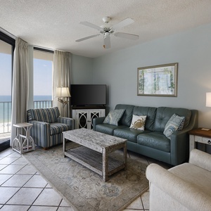 Cozy living area features a teal sofa, striped chair, and stunning gulf views, creating a serene retreat