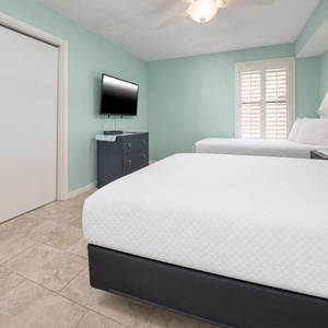 This bright guest room features a full and a twin bed, a flat-screen TV, and a soothing aqua color scheme