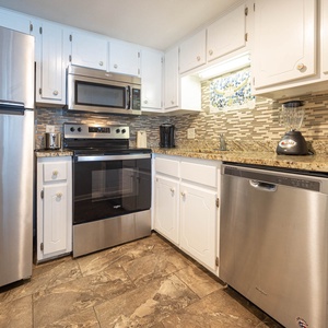 This kitchen features stainless appliances, granite countertops, and a stylish backsplash, perfect for meal preparation