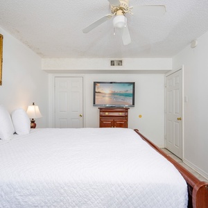 The master bedroom features a floral-patterned bedspread, a wall-mounted TV, and an adjoining bathroom for added convenience