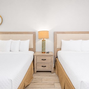 Inviting guest room featuring two queen beds, stylish lighting, and decorative mirrors for a relaxing stay