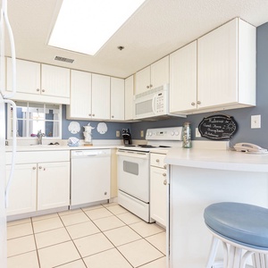 Prepare meals in the kitchen featuring white cabinetry, white appliances, and a convenient breakfast bar