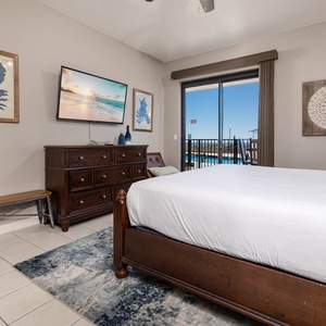 Master suite with a comfortable king bed, stylish decor, and a view of the beach and outdoor pool area