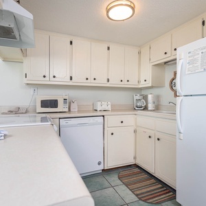 This kitchen features white appliances and ample counter space for preparing meals during your stay