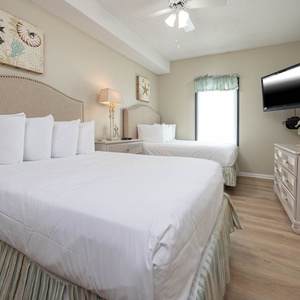 Enjoy restful nights in this cozy guest bedroom featuring two double beds, soft linens, and a wall-mounted TV