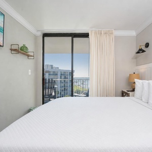 Cozy master bedroom featuring a king bed, wall-mounted TV, and a lovely view from the sliding glass balcony doors