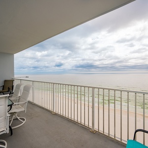 This balcony features comfortable seating and a stunning beachfront view, perfect for relaxing and enjoying the scenery