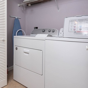 Laundry area featuring a washer and dryer, with an ironing board and storage space for convenience during your stay