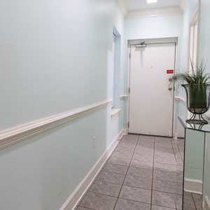 Brightly painted walls and tiled flooring lead to the entrance, featuring a stylish console table and a decorative plant