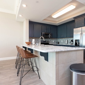 Savor fresh coffee while seated at the inviting breakfast bar, surrounded by the luxurious kitchen space