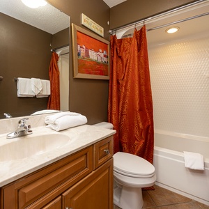 Indulge in a refreshing shower beneath soft lighting, with a touch of warmth in this guest bath