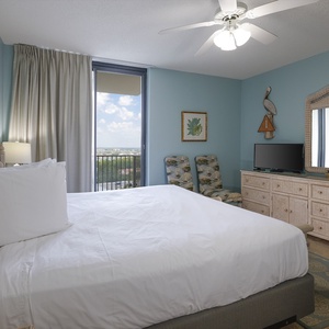 Cozy master bedroom featuring a king bed, tropical decor, and a view from the sliding glass door