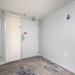 Welcoming entryway featuring a light blue wall, a patterned rug, and nautical-themed hooks for a beach-inspired vibe