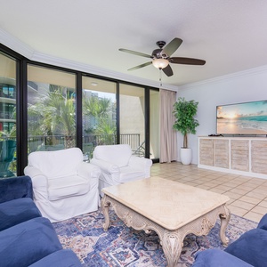 Unwind in the inviting living area, enjoying the gentle breeze and palm views through expansive glass doors