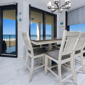 Dining area features a light wood table with chairs and a bench, offering views of the beach through sliding glass doors