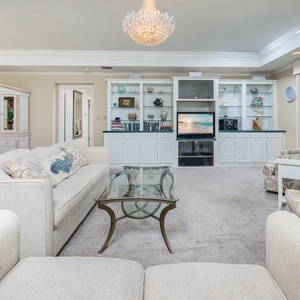Relax in this spacious living area, featuring plush seating, a glass coffee table, and a stylish entertainment unit