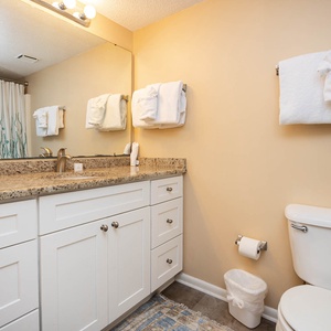Granite countertops and a large mirror enhance this guest bathroom featuring a tub/shower combo and fresh towels