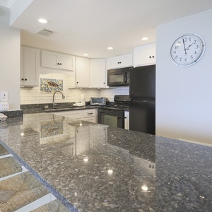 This kitchen features sleek black appliances, granite countertops, and a stylish backsplash, perfect for culinary adventures