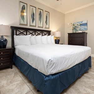 This bedroom features a plush king bed with crisp white linens, stylish artwork, and warm lighting for a relaxing retreat