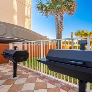 Gather around the grill and enjoy a delightful barbecue at this outdoor seating area, surrounded by palm trees
